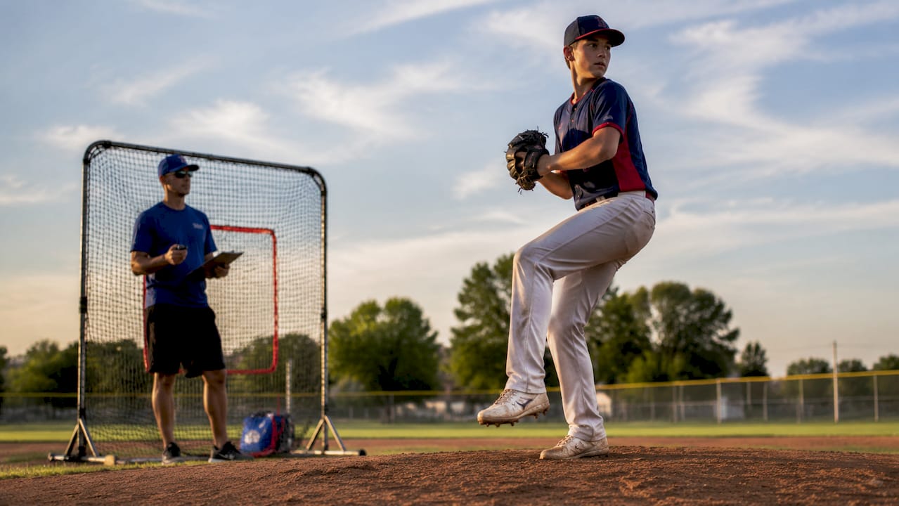Teen pitcher practicing on mound with coach nearby