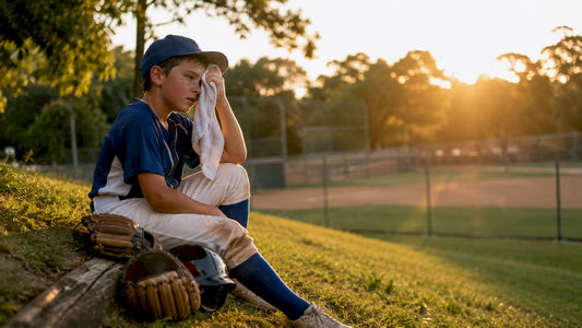 Youth baseball pitcher resting on bench