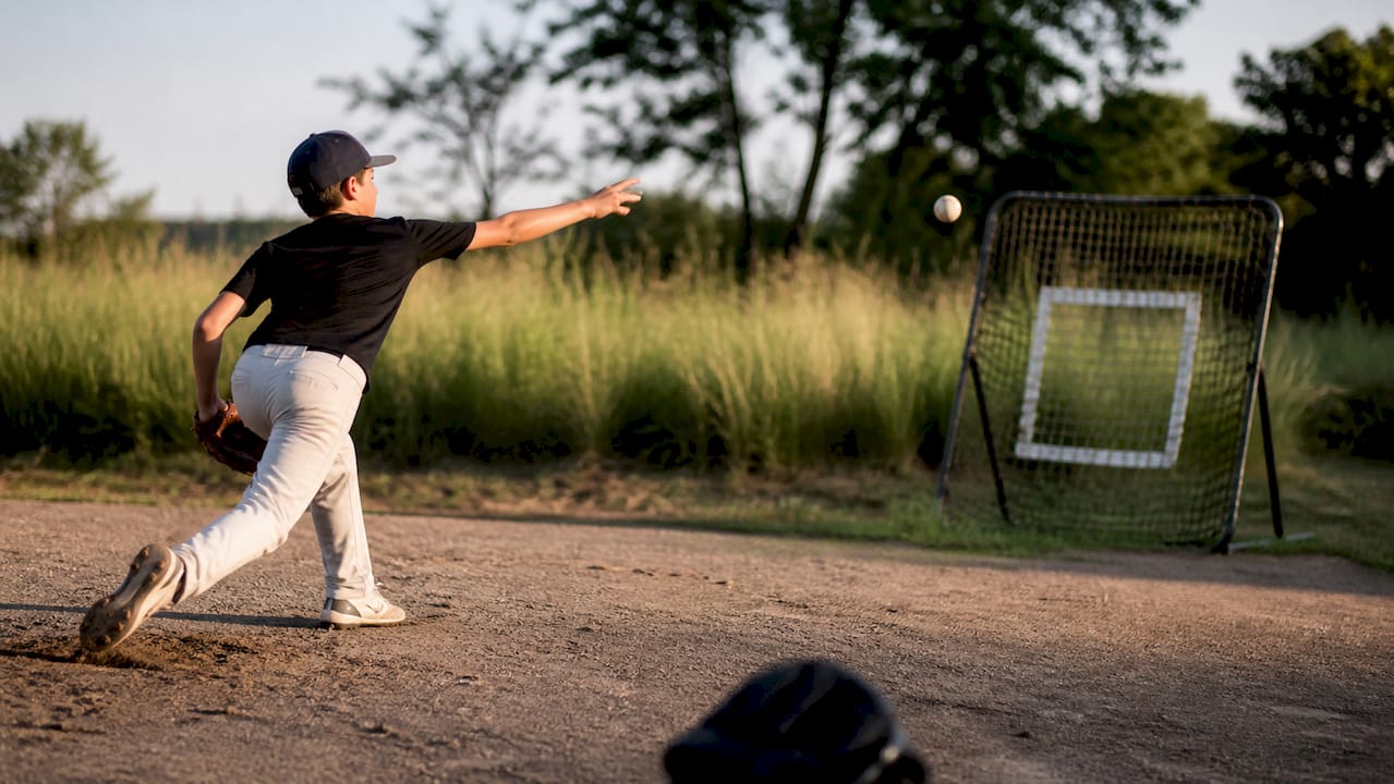 Youth pitcher releasing pitch on baseball field