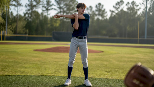 Youth pitcher performing elbow stretch indoors