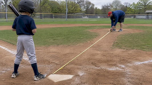 Coach measuring distance to home plate